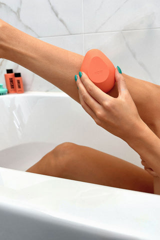 ANSWR exfoliating hair removal frop in hand in a bath tub